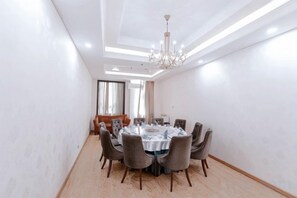 Un salón de conferencias con una mesa redonda, sillas y una araña.