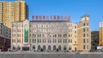 A multi-story hotel with a central entrance, large windows, and a flat roof.