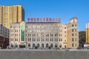 Un hotel de varios pisos con entrada central, amplias ventanas y techo plano.