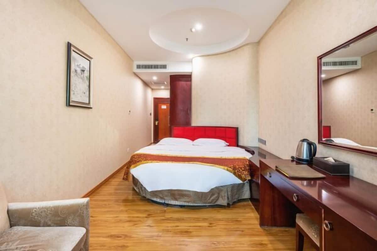 Ein Hotelzimmer mit Bett, Schreibtisch, Stuhl und einem großen Spiegel.