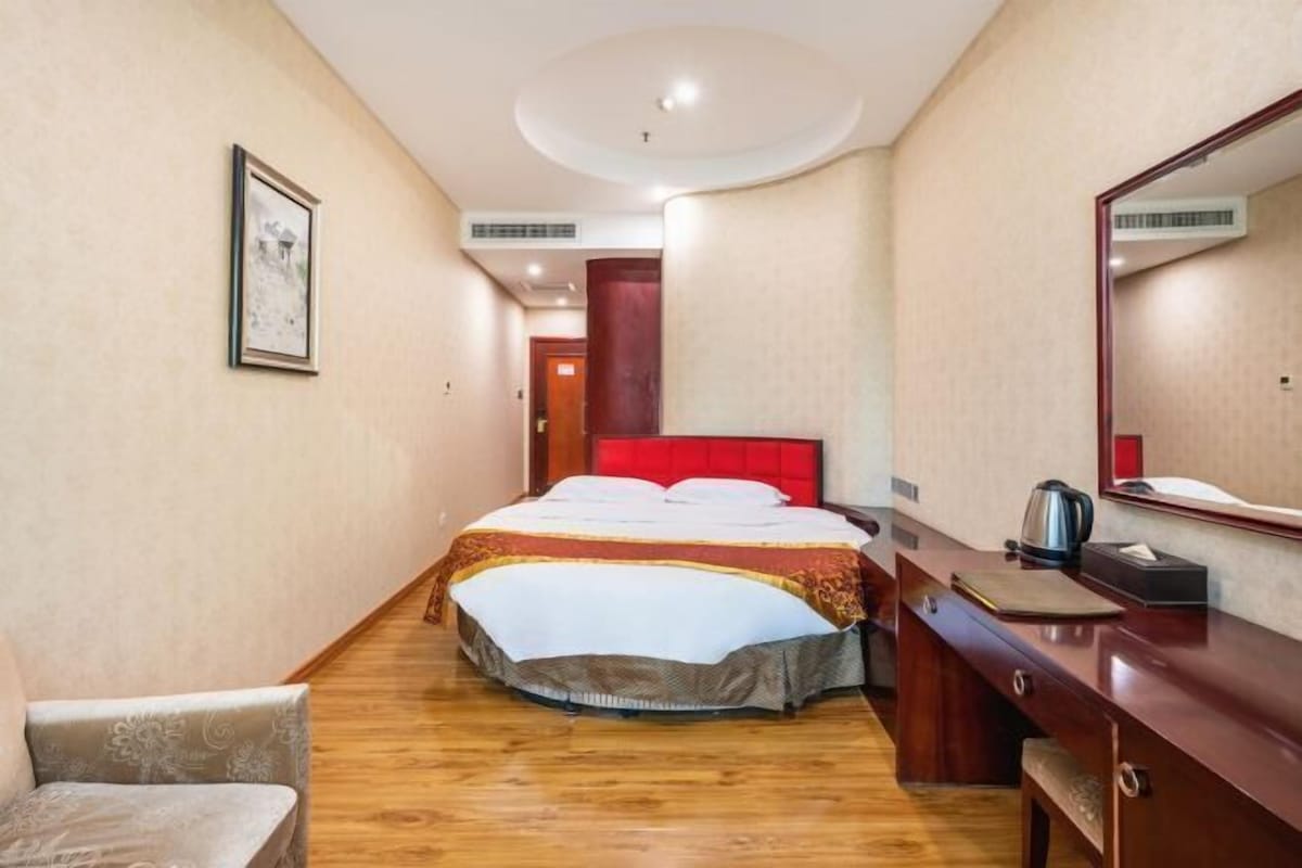 Una habitación de hotel con una cama, un escritorio, una silla, un espejo y un cuadro en la pared.