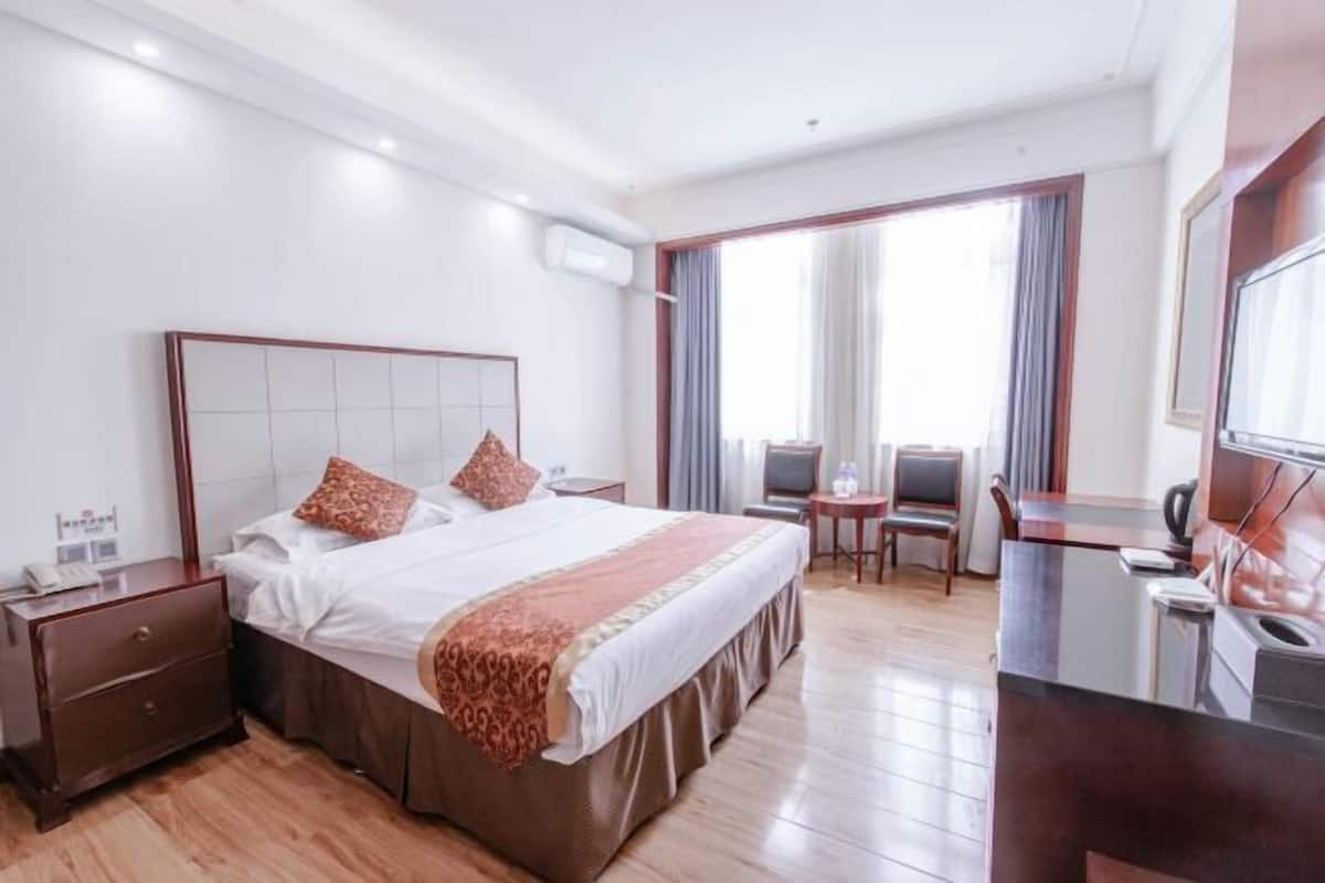 Ein Hotelzimmer mit einem großen Bett, einem Schreibtisch, einem Sessel und einem Fernseher.