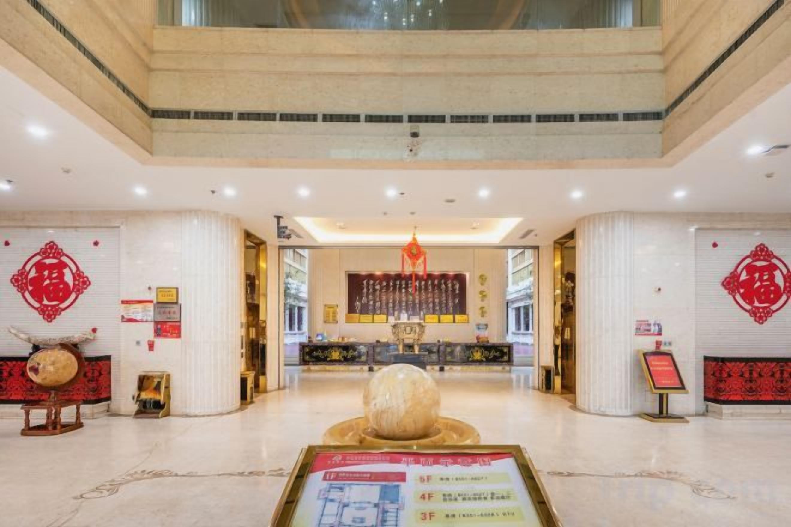 A spacious lobby with a reception desk, a large decorative fountain, and traditional Chinese decorations.