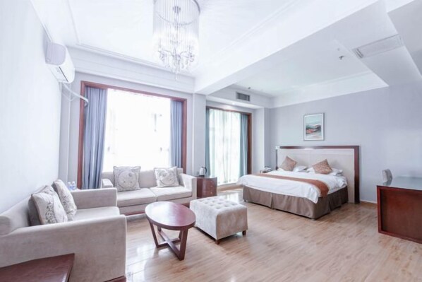 Habitación de hotel con sofá, reposapiés, cama y candelabro.