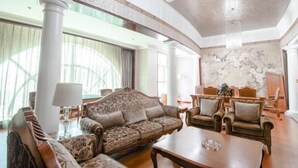 Una habitación amplia con un gran ventanal, un conjunto de sofás, una mesa de centro y un candelabro.