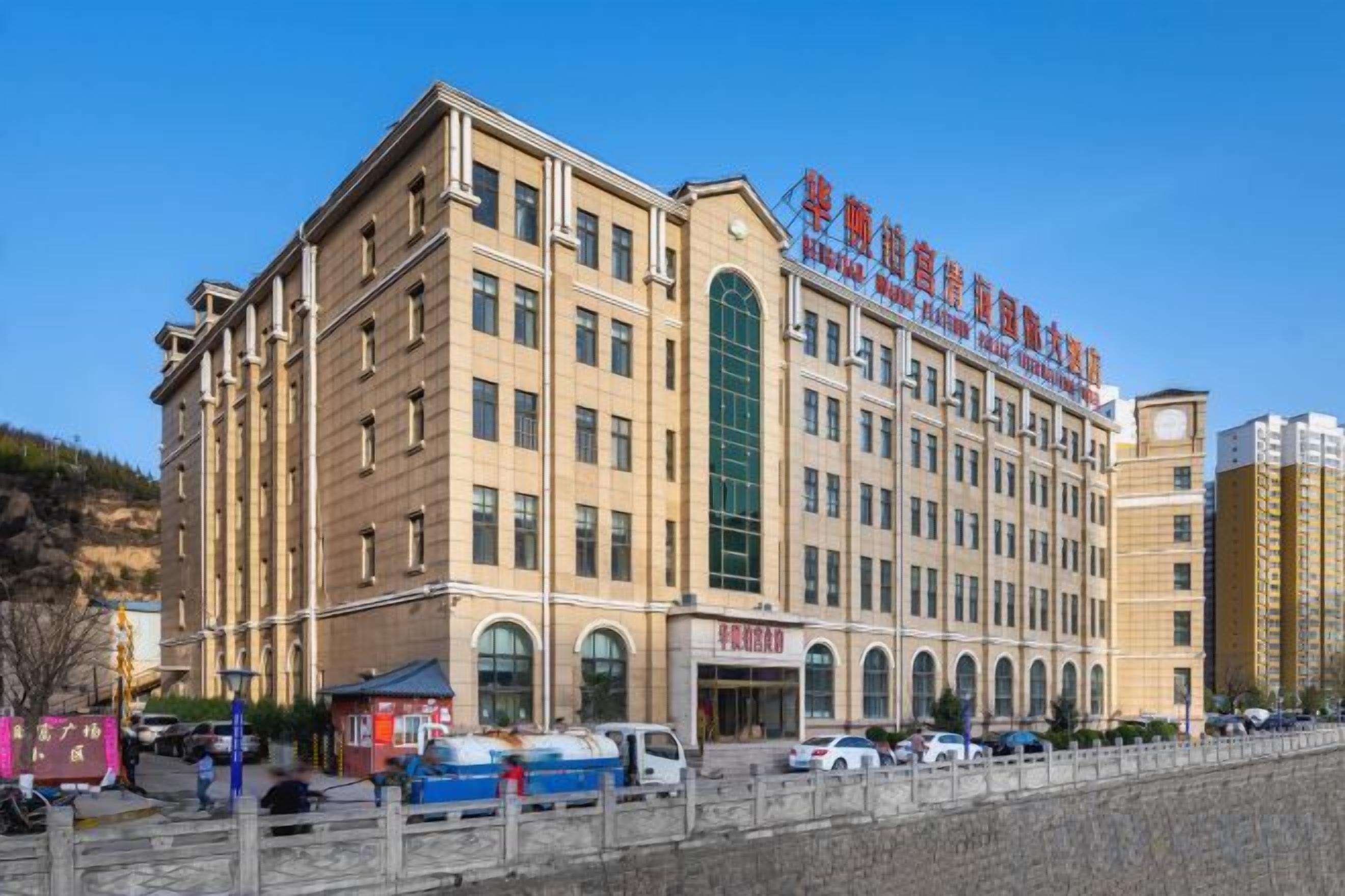 A multi-story hotel with a prominent entrance, large windows, and a clear sky.