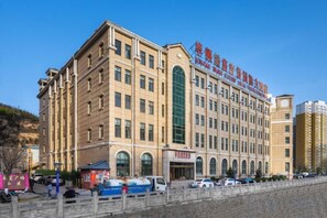 A multi-story hotel with a prominent entrance, large windows, and a clear sky.