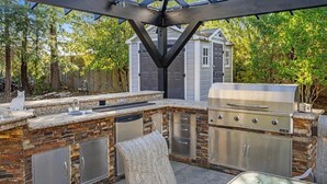 An outdoor kitchen with a grill, a sink, and a stone backsplash. - Family Retreat in the Heart of Wine Country  (Santa Rosa)