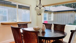 A dining area with a round table, six wicker chairs, a coffee pot, and a wall-mounted light fixture. - Family Retreat in the Heart of Wine Country  (Santa Rosa)