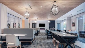 A modern conference room with a long table, chairs, a sofa, and a TV screen.
