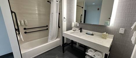 Un baño moderno con ducha a nivel, tocador con espejo y perchero.