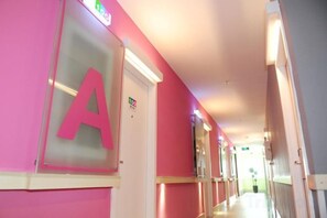 A corridor with a prominent 'A' sign on the wall, a door with an exit sign, and a hallway leading to another room. - 100 Hotel (Guangzhou Panyu Shiqiao Metro Station) (Guangzhou)