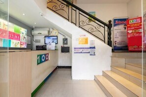 A reception area with a counter, a staircase, and a poster on the wall.