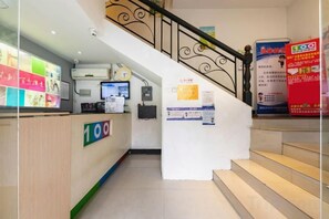 A hotel reception area with a reception desk, a staircase, and a poster on the wall. - 100 Hotel (Guangzhou Panyu Shiqiao Metro Station) (Guangzhou)