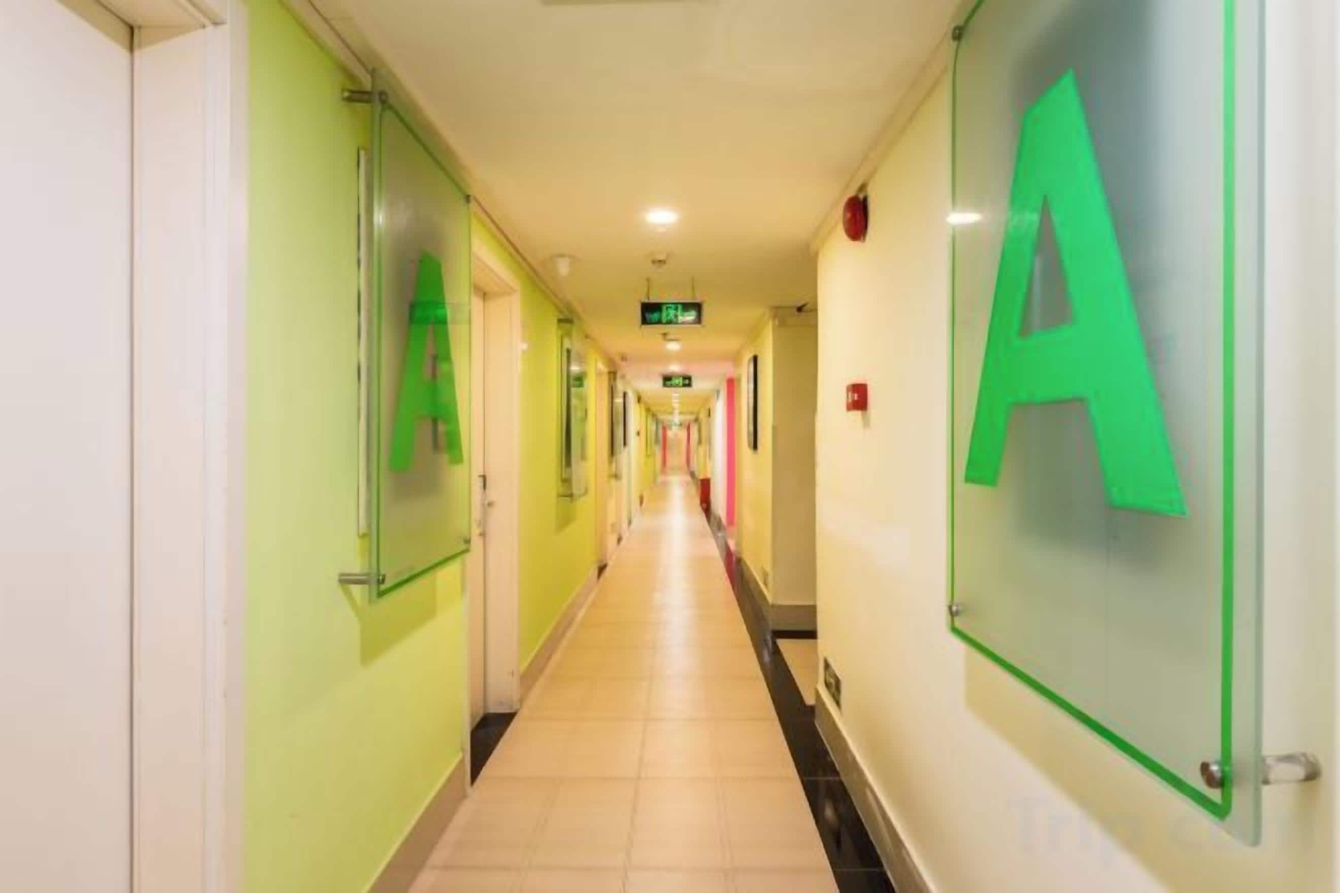 A hotel corridor with green walls, a tiled floor, and a large 'A' sign on the right.