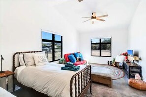 Relax in this serene bedroom with a large bed, ceiling fan, and comfortable seating area.