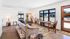 A spacious living room with a sofa, chairs, a coffee table, and a large window providing a view of the outside.
