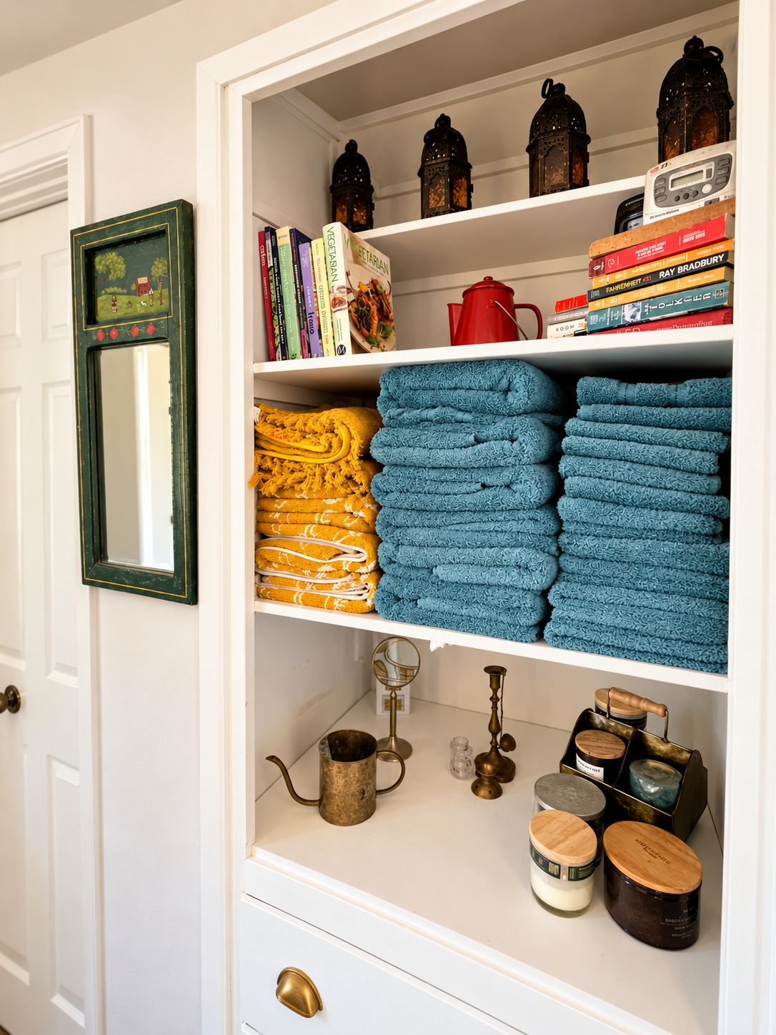 A bookshelf with books, a mirror, and neatly folded towels.