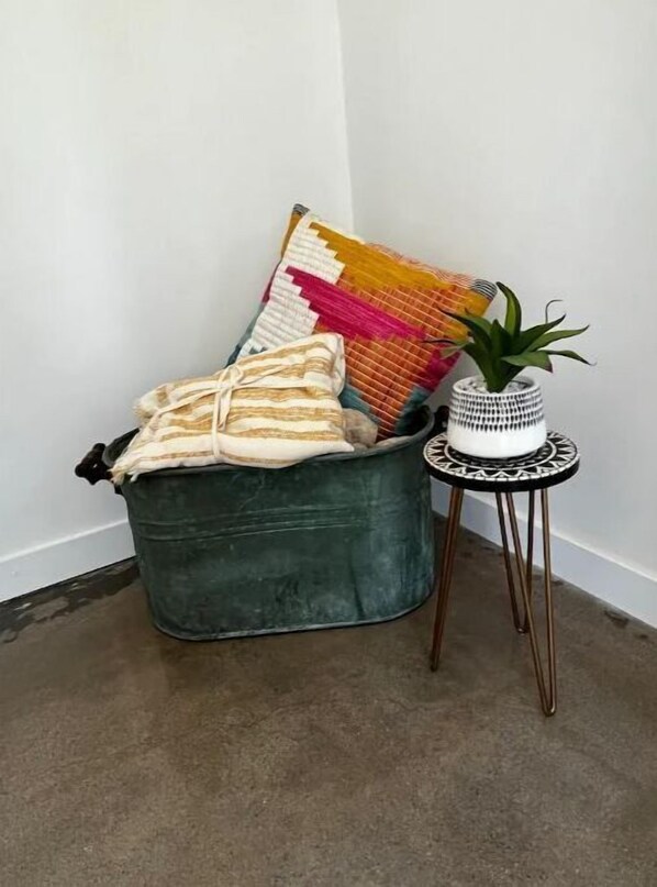 A corner with a green upholstered bench, a colorful woven throw, and a small table with a potted plant.