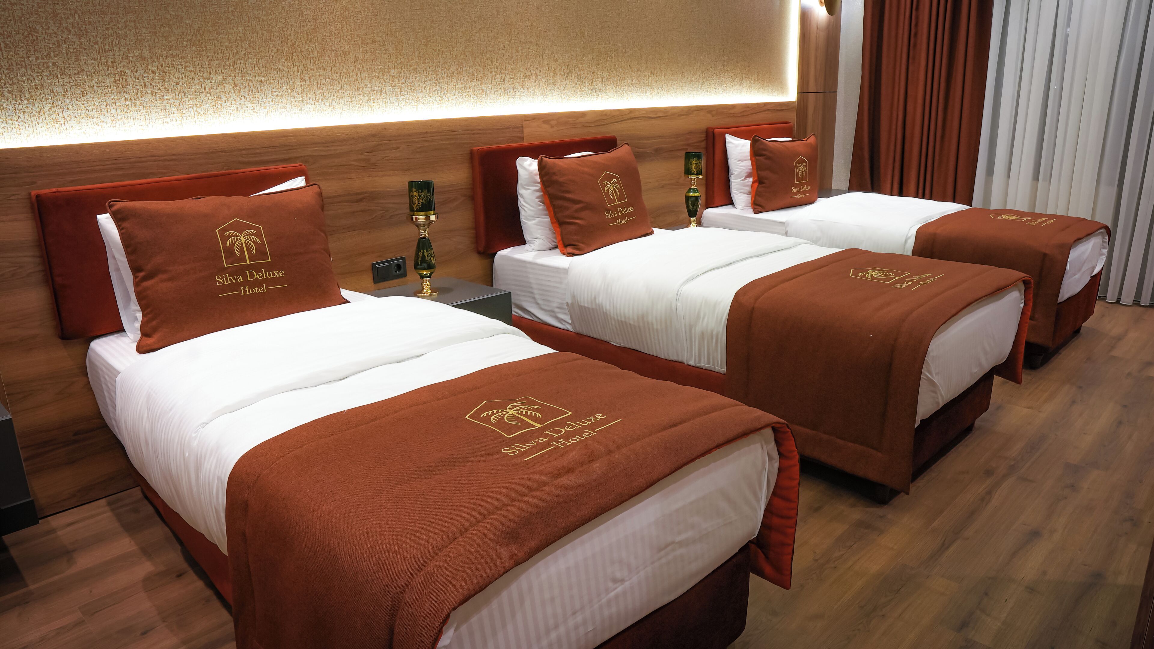 Una habitación de hotel con tres camas, cada una con una colcha marrón y almohadas a juego.