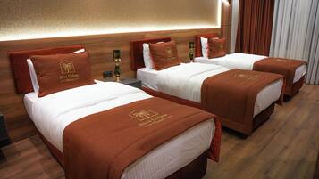 Una habitación de hotel con tres camas, cada una con una colcha marrón y almohadas a juego.