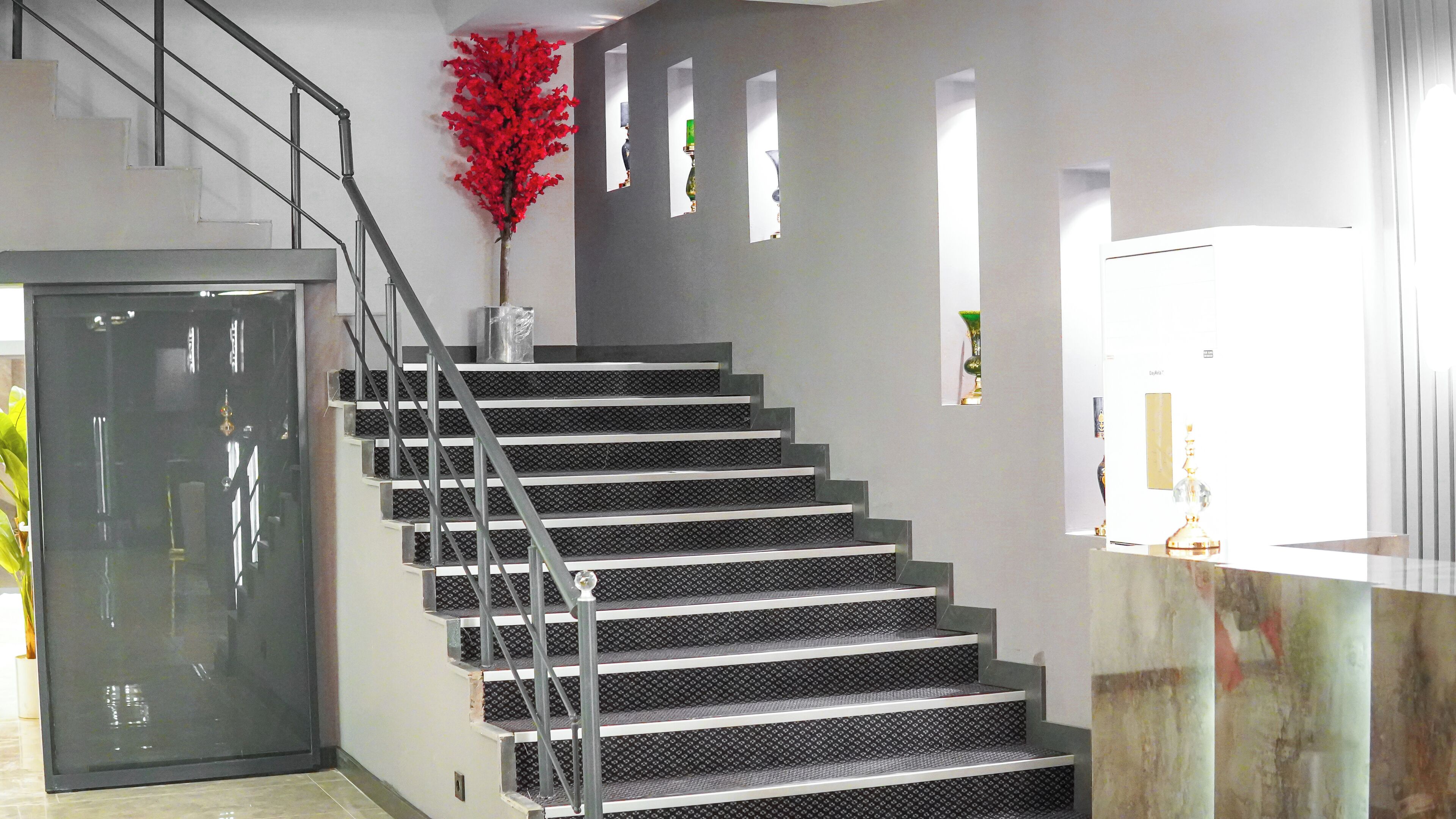 A staircase with metal railings and a red decorative plant.
