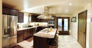 A modern kitchen with a central island, stainless steel appliances, and a large window.
