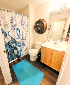 A bathroom with a toilet, sink, and a shower curtain with nautical designs. - Our Napping House, 5 min from Bethany beach, Sleeps 10, Pool, Pickleball, wifi (Ocean View)