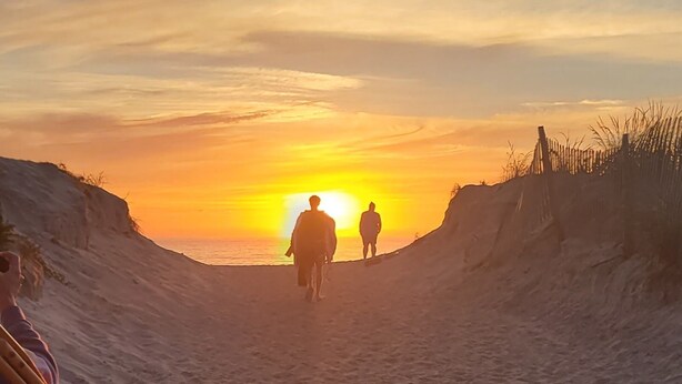 Un atardecer sobre una playa arenosa con dunas.
