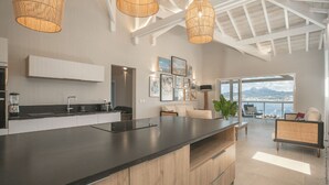 A modern kitchen with a large island, pendant lights, and artwork on the walls.