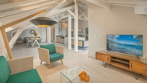 A spacious living area with a high ceiling, a television, and a dining area with a table and chairs.