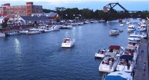 Boats dock along the river, offering scenic views of the bustling waterfront and a nearby bridge.