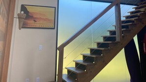 Un intérieur moderne avec un escalier en bois, un plafond en béton et une grande fenêtre donnant sur le ciel.