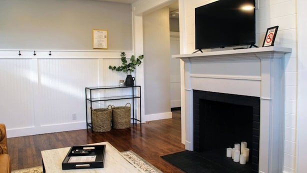 A living room with a fireplace, a television, and a small table with a tray. - Mall St · Cozy Haven In The City W/Deck <5 min to DT Knox (Knoxville)