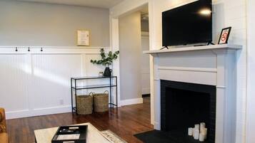 Una sala de estar con chimenea, televisión y una mesita con bandeja.