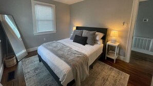A bedroom with a bed, a nightstand, a ceiling fan, a window with blinds, and a door. - Mall St · Cozy Haven In The City W/Deck <5 min to DT Knox (Knoxville)