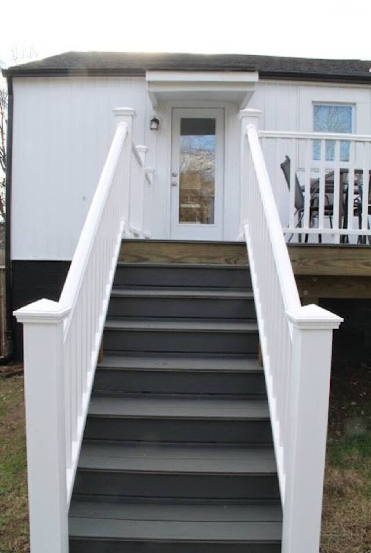 Una escalera que conduce a un edificio blanco con una puerta y ventanas.