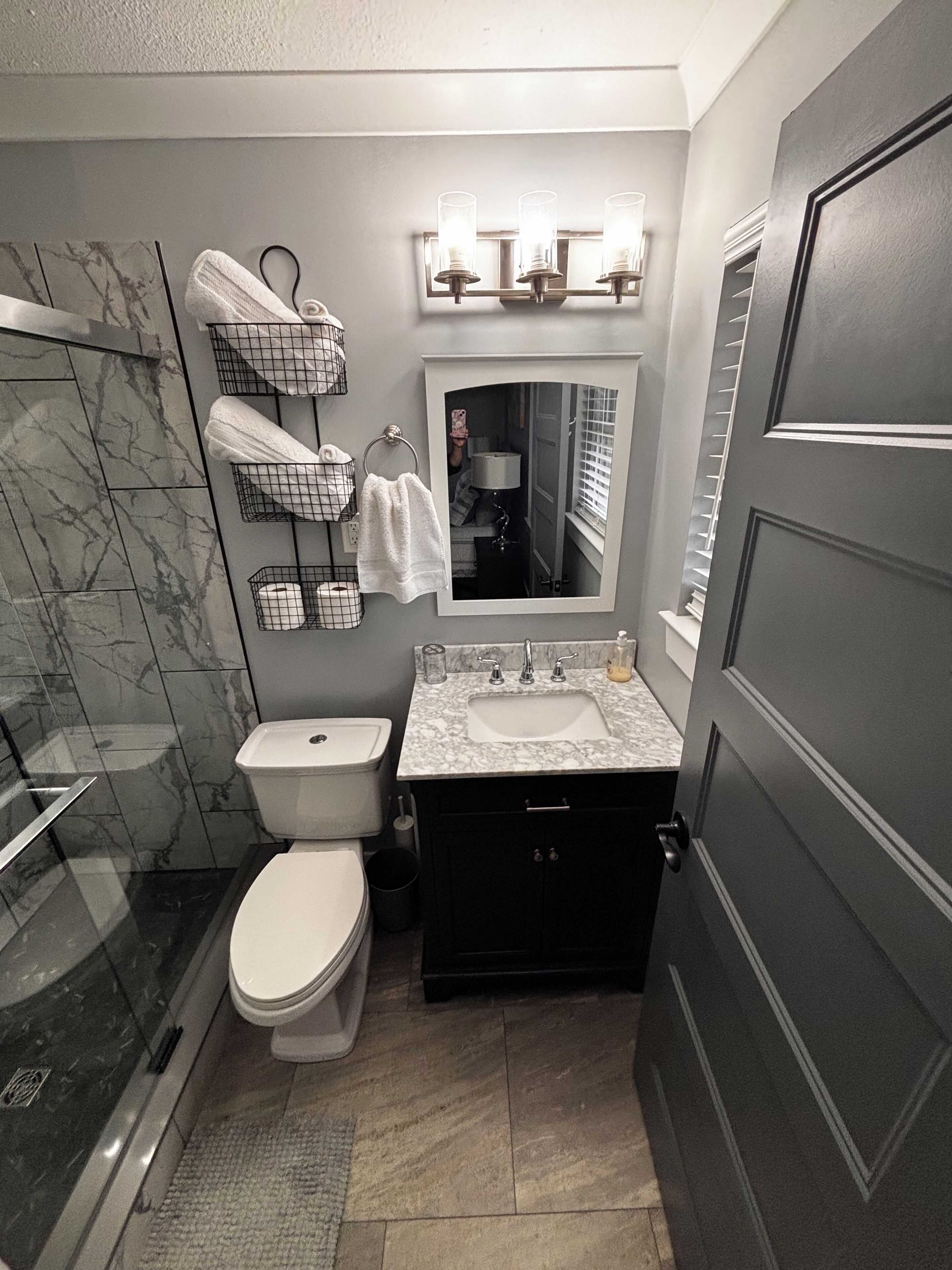 A bathroom with a toilet, sink, and shower. There are towel racks and a mirror above the sink.