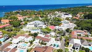 Un área residencial costera con casas, un edificio grande con techo verde y vista al océano.