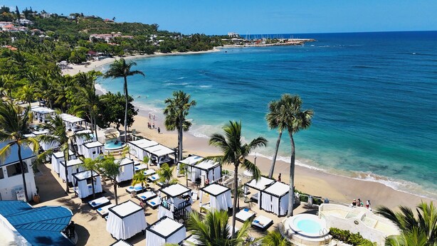 Un resort en la playa con varias cabañas, una zona de piscina y vistas al océano.