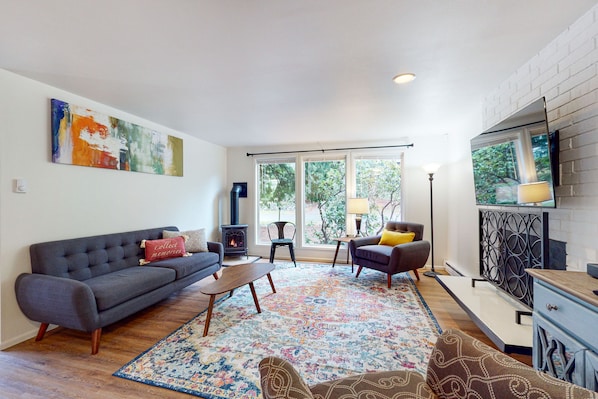 A living room with a sofa, armchairs, a coffee table, a patterned rug, a fireplace, and a TV.