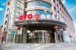 A modern building with a prominent 'OYO' sign, featuring a circular entrance and glass facade. - Xinluyuan Hotel (Tumed Right Banner)
