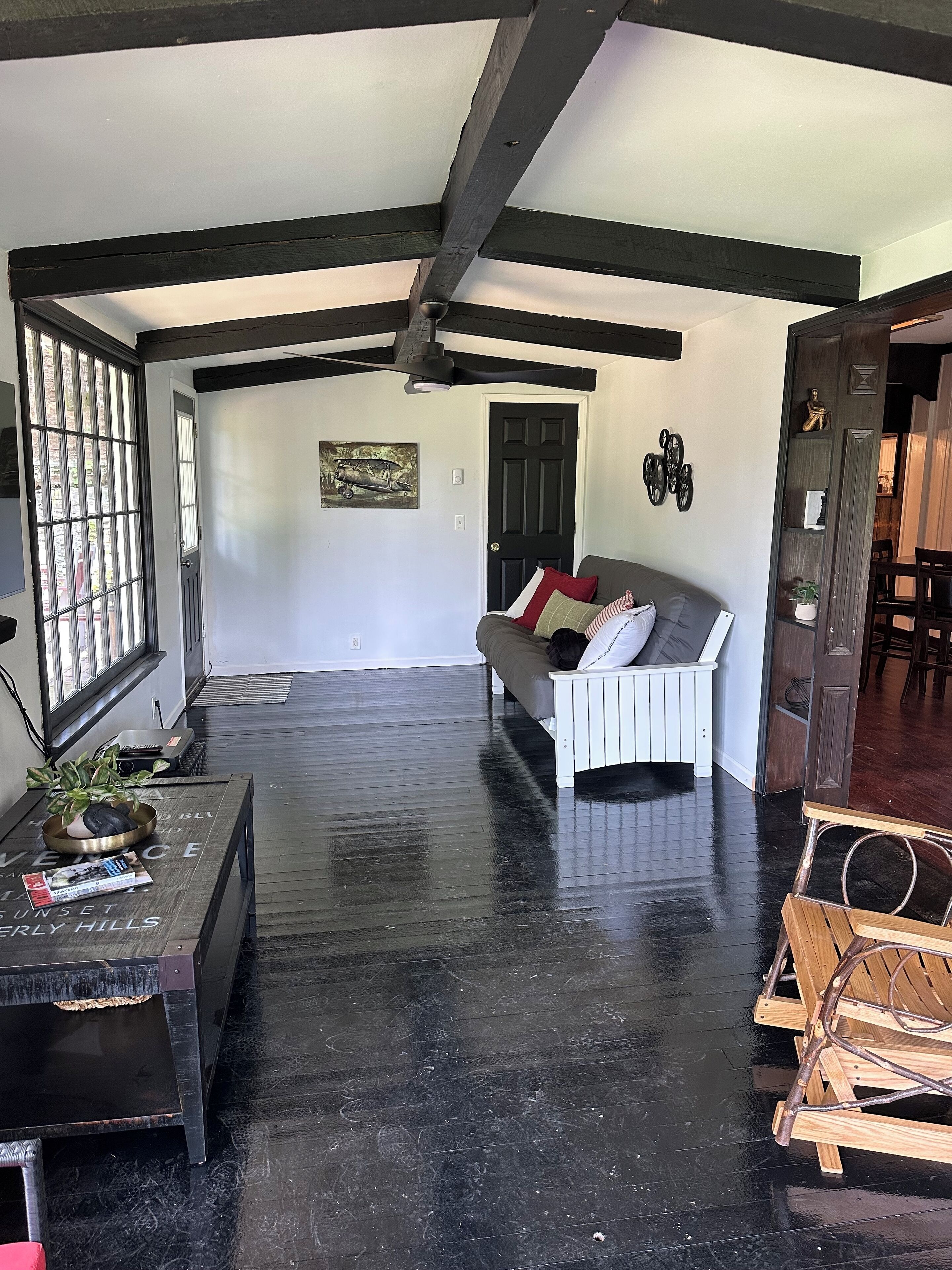 A spacious living room with a black and white color scheme, a wooden floor, a sofa, a coffee table, and a door with a window.
