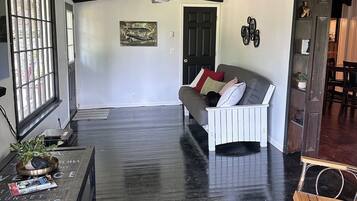 A spacious living room with a black and white color scheme, a wooden floor, a sofa, a coffee table, and a door with a window.