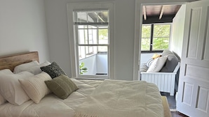 Une chambre à coucher avec un lit en bois, des murs blancs et une vue sur un balcon.