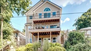 A multi-story building with a balcony on the upper floor, surrounded by greenery. - Beautiful House overlooking Lake Chemung, with a Private Chef Tasting option. (Howell)