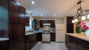 A modern kitchen with dark wood cabinets, a stainless steel stove, and a white refrigerator. - Beautiful House overlooking Lake Chemung, with a Private Chef Tasting option. (Howell)