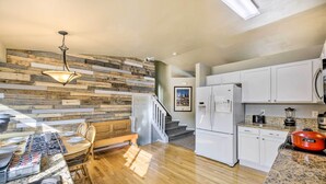 Una cocina moderna con detalles de madera, armarios blancos y encimera de granito.