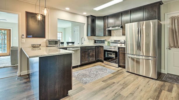 A modern kitchen with dark cabinetry, stainless steel appliances, a large island, and pendant lighting. - Waterfront Retreat < 4 Mi to Dtwn Cambridge! (Cambridge)