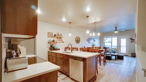 A modern kitchen with wooden cabinets, a dishwasher, and a dining area with a table and chairs. - Lovely McCall Retreat < 2 Mi to Payette Lake! (McCall)